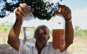 Villager holding two bottles, including one with polluted waters. Photo by: Rosilene Miliotti /FASE